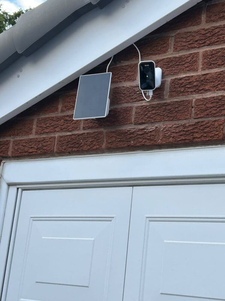 A solar panel and wireless security camera fitted above a garage door